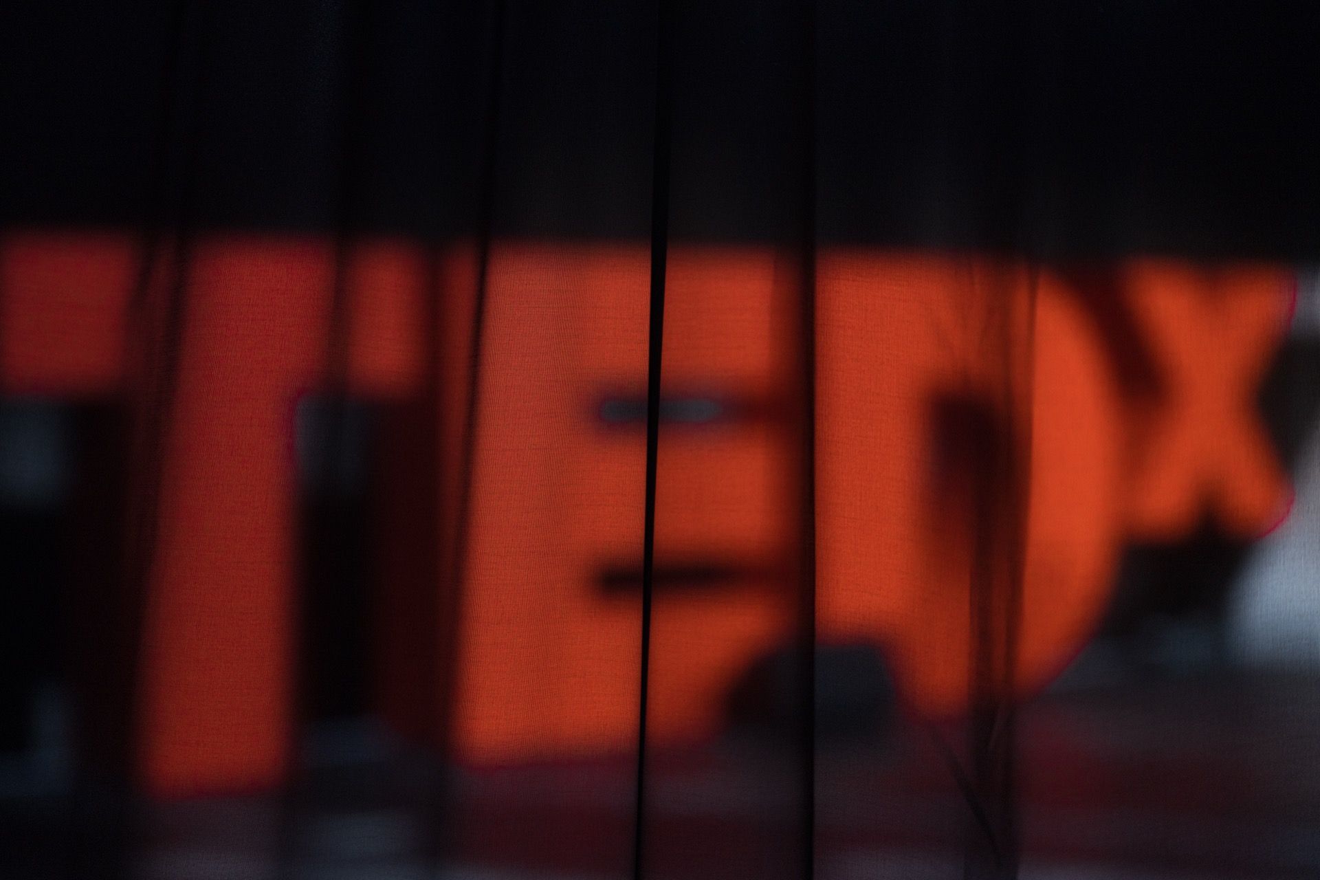 A large red TEDx sign glowing behind dark stage drapes